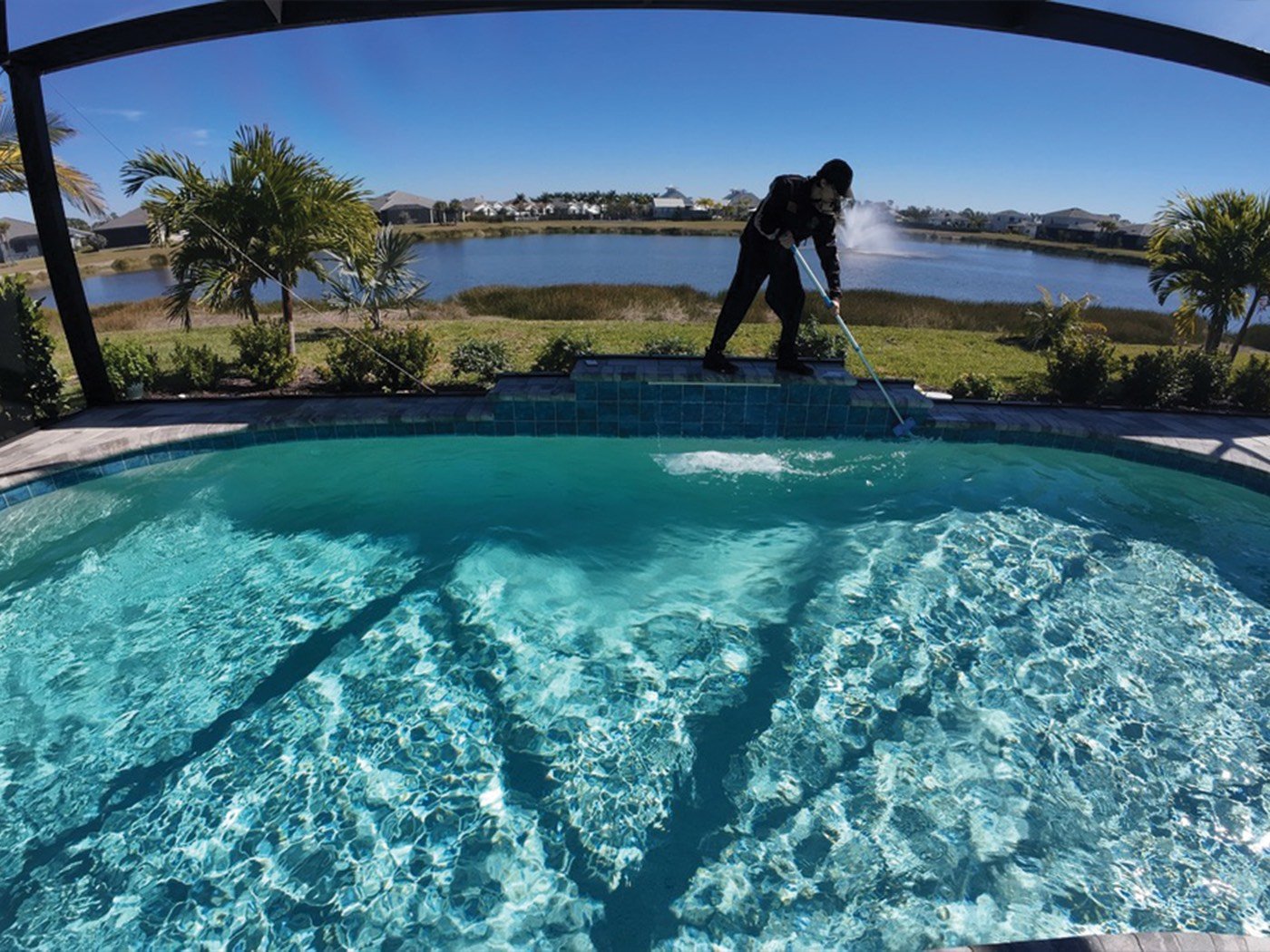 Technician vacuuming a pool overlooking a lake